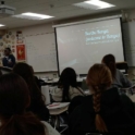 Eddah from Kenya stands in front of a screen at the front of the classroom. The image on screen reads Welcome to Kenya