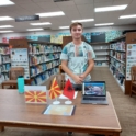 Lavdrim Standing In A Libray During IEW Behind A Table sharing Information about N  Macedonia