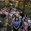 Alumni standing in a group with masks on in a restaurant. 