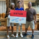 Muhammad standing next to his host parents, holding a sign that says "welcome to the USA"