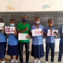 Nike and others hold up pieces of paper in a classroom while masked