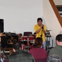 Mahir holding a microphone and speaking at the front of a stage full of audience in an auditorium. 