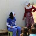 Project Leader Hala Allawama Sits In Front Of A Group Of Kids Who Are Listening And Learning