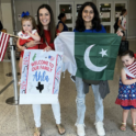 Ahla holding a Pakistani Flag standing next to her host family at the airport.