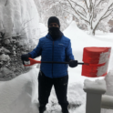 Hussain standing with a snow shovel surrounded by many feet of snow