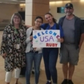 YES student posing with her host family and host sister, holding a sign that says "Welcome to USA Ruby"