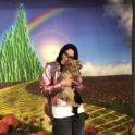 Sidrah holding a small brown dog in front of a backdrop from the Wizard of Oz