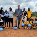 The US. Ambassador to Liberia stands with youth holding soccer balls