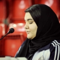 Close up of young woman in black headscarf in front of red bleachers