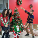 Three Young People Standing With A Decorated Christmas Tree And A Small Santa Statue