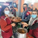 Alumni standing next to a table with masks on preparing to hand out soup. 