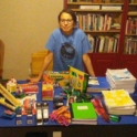 A YES alumna standing behind a table full of school supplies