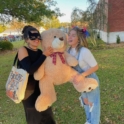 Two Young Women In Costumes Holding A Large Teddy Bear