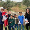 Two Young Women Standing With A Group Of Children Holding Bags Of Goodies