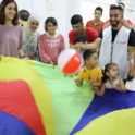 YES volunteers and children smile while playing with a colorful parachute
