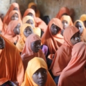 A group of young girls, wearing orange Hijabs, sitting in rows