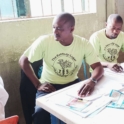 YES alumni volunteers attentively observe as a patient receives counseling on his medication during a health screening event
