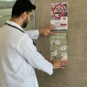 YES alumnus in a doctors coat hanging a flyer on the wall