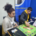 Young Man And Woman With A Monopoly Board In Front Of Them