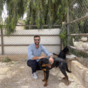 Young Man Standing With A Brown And Black Dog