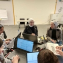 Young Women Sitting At A Round Table With Laptops