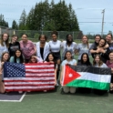 Group of high school tennis players hold up Jordanian and American flags on a tennis court