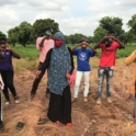 Owou Atwedie Aid Project participants stand in a field with their hands raised.