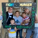 YES student stands with his host family in front of a step in that says "fight hunger make a difference"