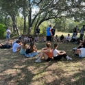 Picture of Ryan and students in a group circle in the woods.