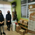 Two women in masks, standing next to piles of donations