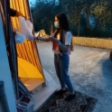 Young woman giving a bag to someone standing inside a doorway