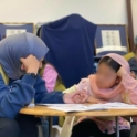 Aljood sits with a young female student helping her study