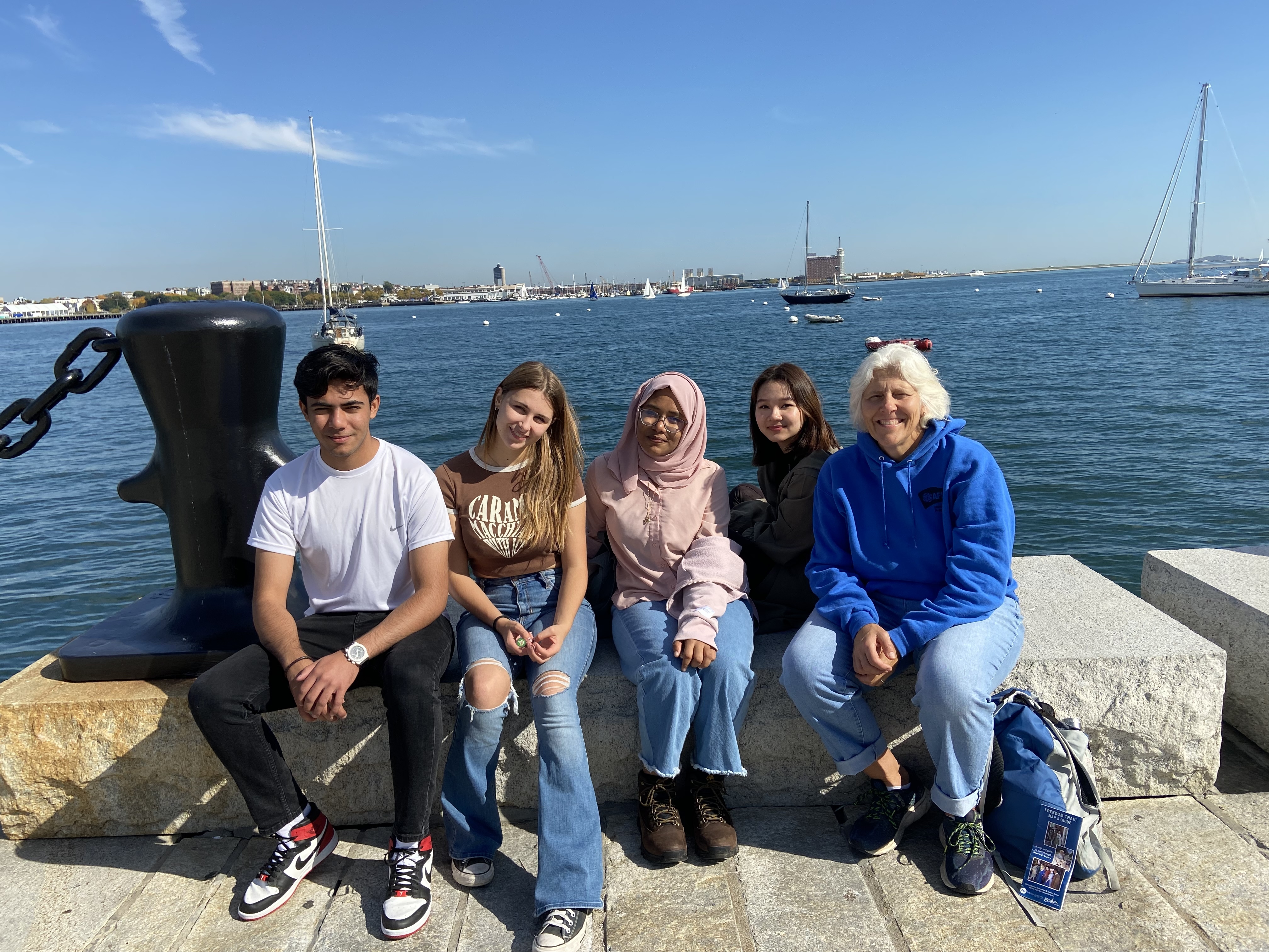 Muhammad smiling with friends on a dock at Boston Harbor