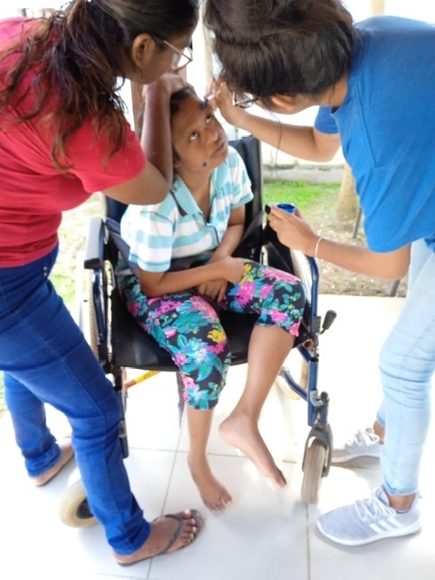 YES alumna with others doing face painting with one of the children at Betheljada.