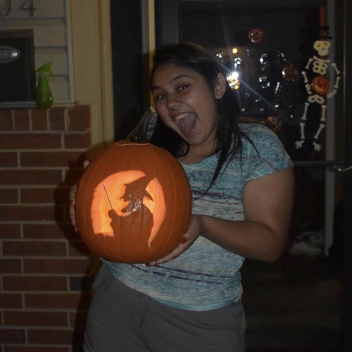 Saba holding a carved pumpkin with a witch on it.