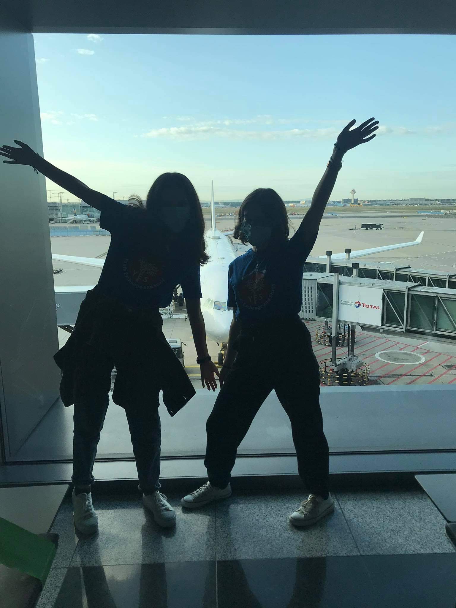 Two YES students' silhouettes in front of an airport window
