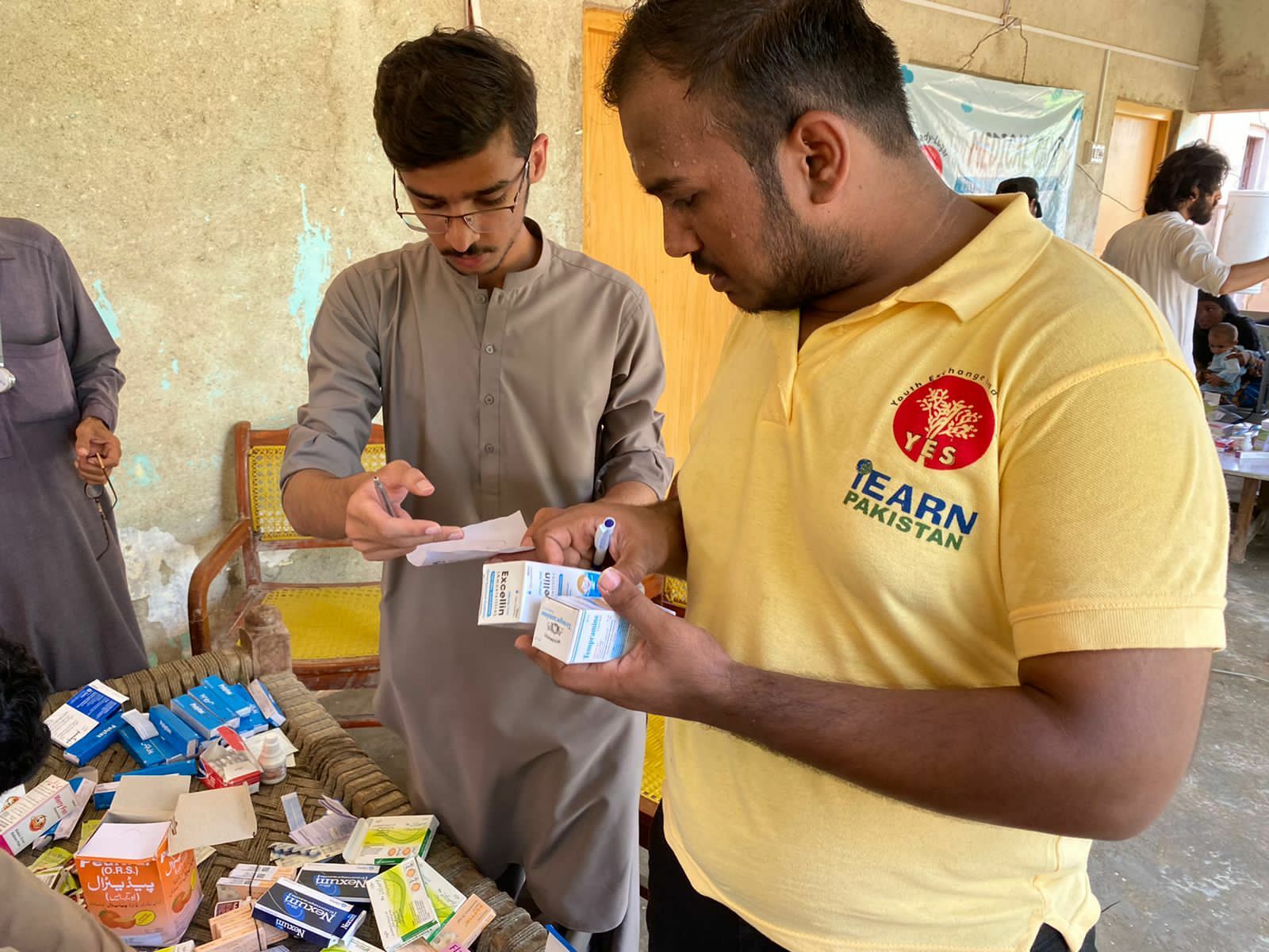 YES Alumnus, Muhammad Sufiyan, and Local Volunteer Shehryar Rind handing out prescribed medicines to the flood affected patients.