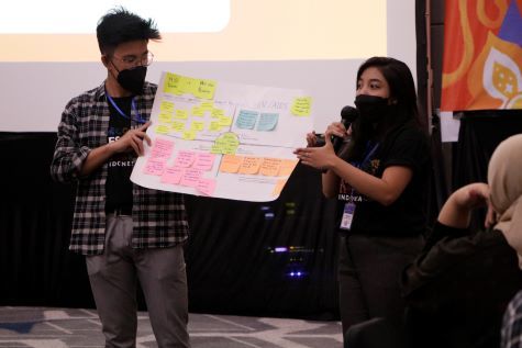 Two people hold poster board with sticky notes