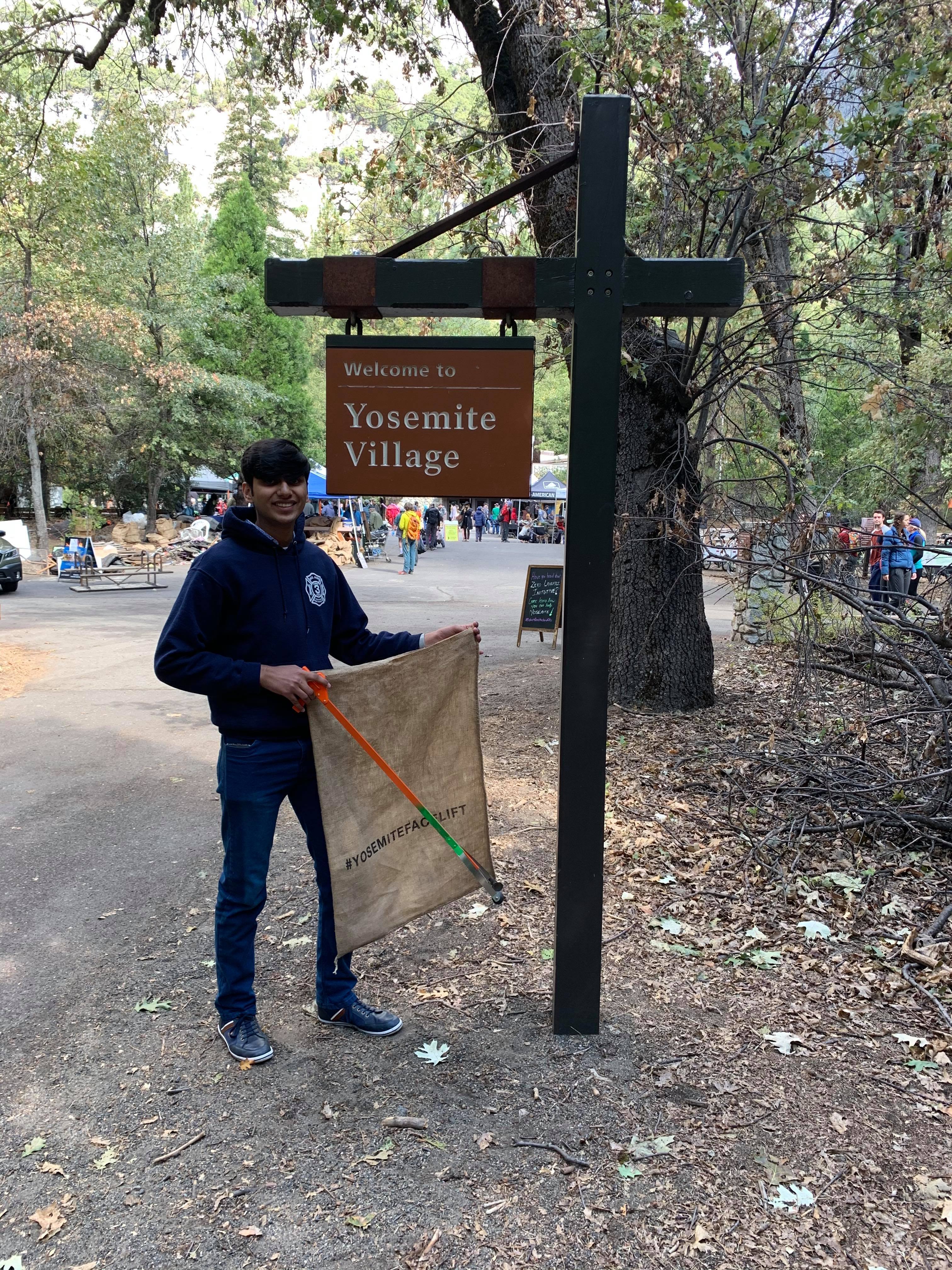 YES student stands next to a sign that says "Yosemite Village"