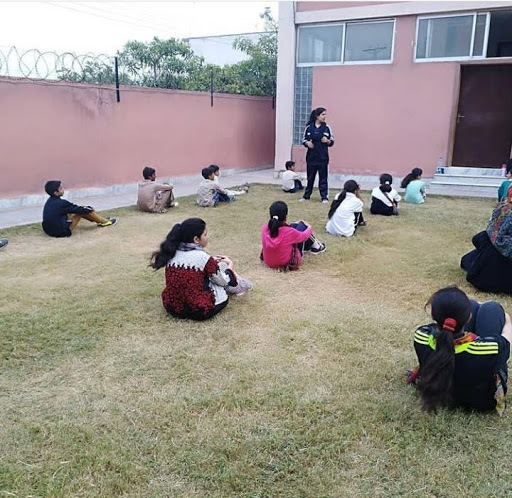 Samman instructs students, who sit on the grass listening. 